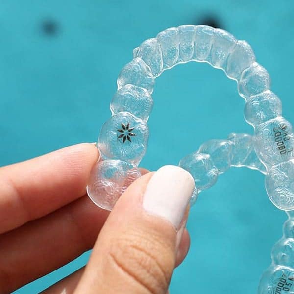 Dentist holding an Invisalign clear aligner in Calgary