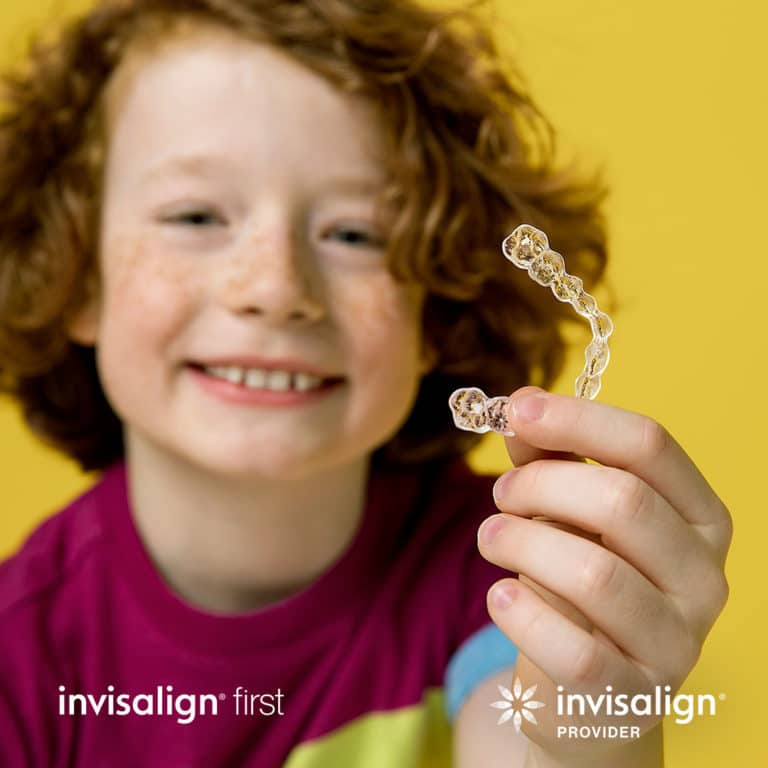 a child holding an Invisalign clear aligner in Calgary